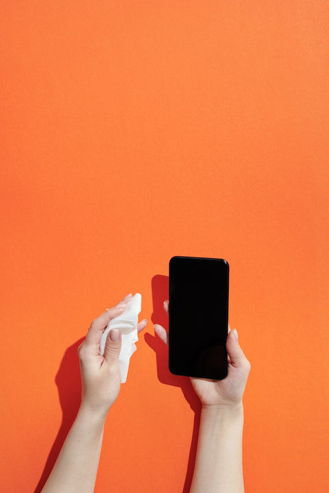 A person holding a phone in their right hand and a sanitizing wipe in the left hand